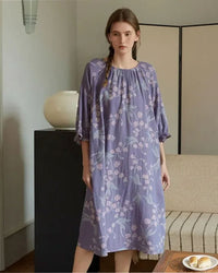 Woman relaxing at home in a lightweight cotton nightgown, dreamy purple floral pattern and easy round neck make it ideal warm-weather sleepwear.