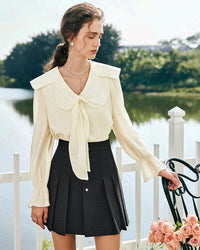 Women's elegant cream lace blouse featuring a romantic V-neckline with bow detail, long balloon sleeves with ruffled cuffs, and delicate tatting craftsmanship — perfect for sophisticated office or dinner date styling.