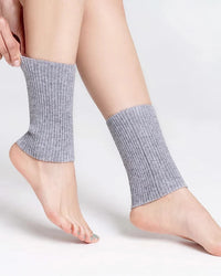 A pair of ribbed wool blend ankle warmers with a 3D stretch wrap, designed for a secure fit that stays put under boots and skirts all day.