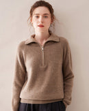 Woman hiking snowy trail in charcoal half-zip cashmere sweater, thick 8-ply knit locks in warmth while mock-neck zip vents heat on the climb .