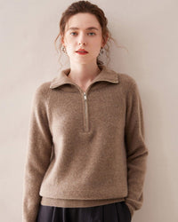 Woman hiking snowy trail in charcoal half-zip cashmere sweater, thick 8-ply knit locks in warmth while mock-neck zip vents heat on the climb .