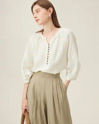 Woman brunching in a sand-beige linen three-quarter sleeve shirt, airy flax fibers and loose cut keep you cool—your effortless staple for 70–85 °F spring-summer days.