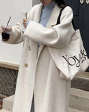 Woman crossing city bridge in camel long double-faced wool overcoat, single-button closure and side slits create fluid movement for winter commutes.