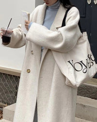 Woman crossing city bridge in camel long double-faced wool overcoat, single-button closure and side slits create fluid movement for winter commutes.