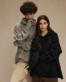 Woman lounging in a sand-beige loose 100 % cotton hoodie, airy French-terry fabric and dropped shoulders give relaxed 90s vibes—perfect breathable layer for 60-75 °F spring-fall days.