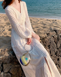 Women's high-end V-neck high-waisted long dress made of thin white hollow lace featuring a flowy silhouette perfect for seaside vacation fashion.