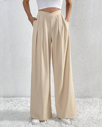 Model wearing high waist wide leg pants with crossover waist detail, paired with white cropped top and white sneakers.