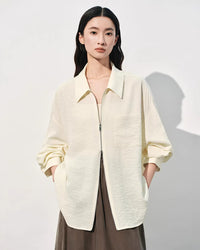 White loose-fit polo-collar zip shirt for women crafted from a premium mulberry silk blend, featuring a textured jacquard finish and a relaxed oversized silhouette.