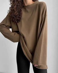 Woman lounging in the 100-Cotton Basic Oversized T-Shirt, 220 g brushed 100 % cotton and boxy drop-shoulders give lived-in 90s vibes—your breathable 70-85 °F summer essential that layers effortlessly under denim jackets .