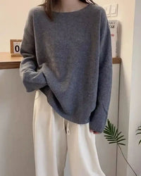 Woman styling an oversized 100 % cashmere boatneck sweater, relaxed drop-shoulder silhouette pairs with denim or satin skirts for effortless cold-weather chic.