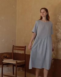 Woman drifting off in a breathable white cotton nightie, tag-free round neck and knee-length drape deliver spa-level softness for sensitive skin.