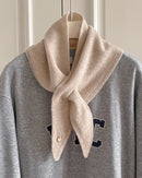  The triangular cut folds naturally around the neck, while a small circular accent adds subtle detail. 