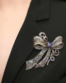 Baroque rhinestone bow brooch in silver tone, elegant metal pin with sparkling crystal accents and intricate ribbon design, perfect for adding glamour.