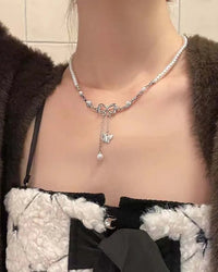 A clavicle necklace featuring a hollow bow pendant with pearl accents and a tassel drop with a butterfly charm, secured with a lobster clasp.