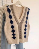 A sleeveless knit sweater vest featuring a deep V-neck with contrast trim and a gingham pattern, offering a relaxed fit for effortless layering.