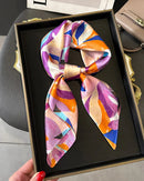 The scarf's smooth, featherlight construction makes it easy to style — draped at the collar, knotted through a bag handle, or worn as a headscarf.