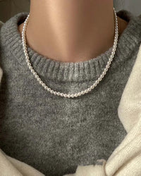 A classic clavicle necklace featuring a strand of lustrous imitation pearls and a sleek magnetic clasp, designed for an elegant, timeless look.