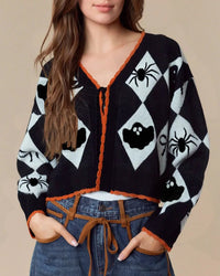 A pumpkin ghost v-neck cardigan with v-neck, pumpkin and ghost motifs, short slim fit and long sleeves, designed for a cozy winter layering look that pairs from sneakers to boots.