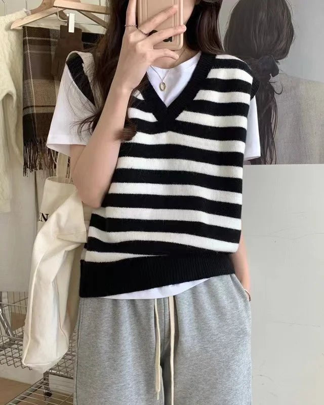 A woman modeling a loose-fit pure wool knitted waistcoat with a classic V-neck and bold striped pattern, layered over a simple white t-shirt.