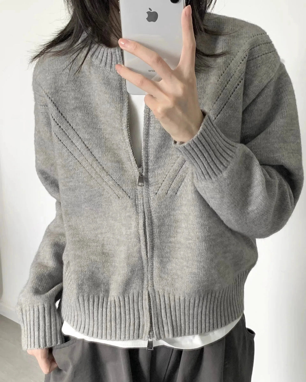A 100% cashmere zip knit cardigan with a thick ribbed texture and short loose fit, designed for office-ready warmth that layers easily over tees.