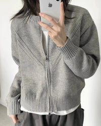 A 100% cashmere zip knit cardigan with a thick ribbed texture and short loose fit, designed for office-ready warmth that layers easily over tees.