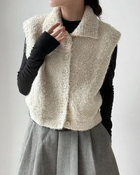 The turn-down collar and single-button front give this sleeveless knit vest a deliberate, considered structure that elevates it beyond the typical layering piece. 