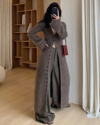 A long knit cardigan featuring a V-neck, an open-front design, and a geometric jacquard pattern, offering a relaxed fit for effortless layering.