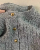A pure cashmere cable-knit cardigan featuring a round neck, gold button closure, and a relaxed fit, crafted for elegant, layered warmth.