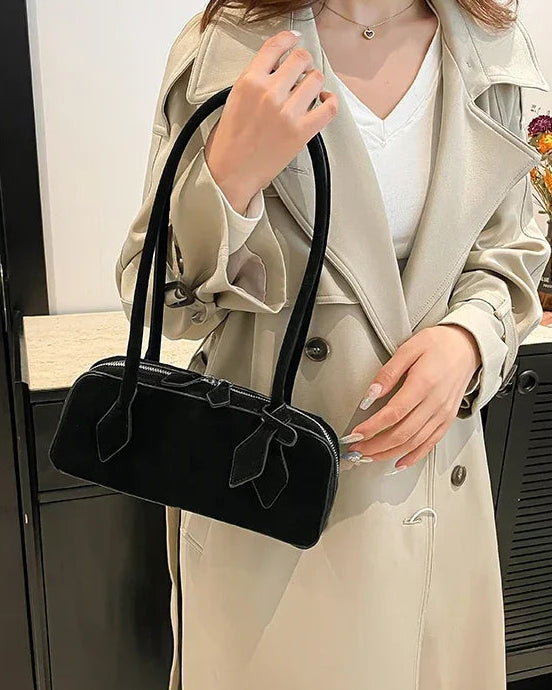 A soft faux suede bowling shoulder bag with secure zipper, two straps and interior compartment, designed for everyday styling that moves from day to night.