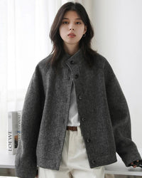 A wool blend short coat featuring a structured stand collar, a concealed front closure, and a relaxed silhouette for a modern and sophisticated look.