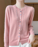A merino wool button-front cardigan with O-neckline, button details and soft seamless knit, designed for a cool-weather layering look that pairs from sneakers to boots.