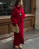The oversized sweater drapes generously over the body, its turtleneck adding warmth and structure, while the matching midi skirt flows softly from an elasticated waist.