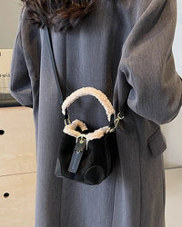 A faux suede bucket shoulder bag with plush lining, a crossbody strap and compact rounded shape, designed for a retro vibe that moves from day to night.