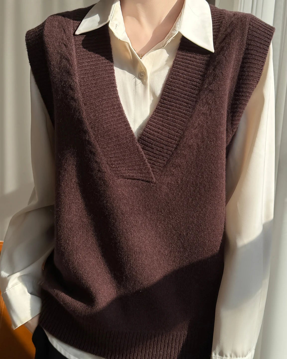 The sleeveless silhouette leaves room for shirts and fine knit tops, while a deep V neckline keeps the look open and uncluttered.