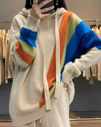 A rainbow wool knit hoodie with rainbow pattern, hood, loose fit, long sleeves and stretch, designed for a cozy winter layering look that pairs from sneakers to boots.