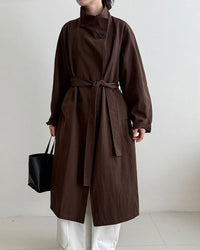 An oversized mid-length trench coat featuring a stand collar, belt-tie waist, and a relaxed fit for a minimalist, all-season look.