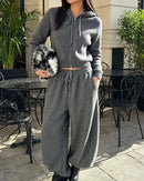 The drawstring hoodie features a clean zip closure and full sleeves, while the elastic-waist trousers skim the ankle in a straight, flattering line.