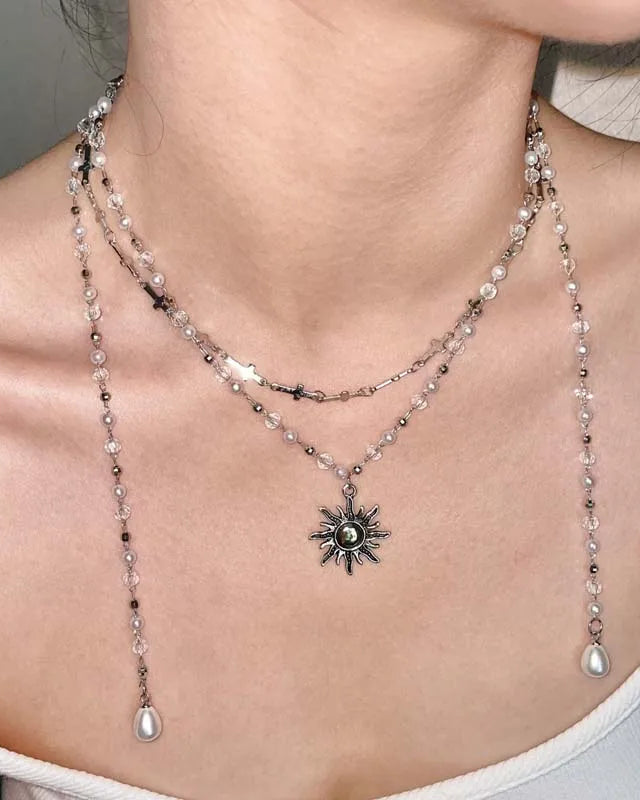 A vintage-inspired necklace featuring a sunburst pendant on a beaded chain with cross details, designed for a bold, gothic punk look.