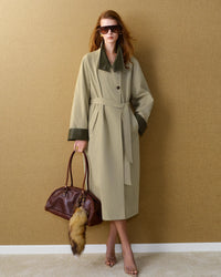 The woven cotton-blend fabric drapes beautifully, while the single-breasted closure and belted waist lend a timeless, editorial quality.