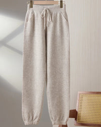 A pair of merino wool drawstring pencil trousers featuring a seamless knit, side pockets, and an elastic waist for a sleek, comfortable fit.