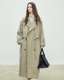 A floor-skimming trench coat with a turn-down collar, double-breasted front, and waist sash, designed for a relaxed, oversized silhouette.