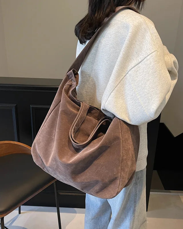 An easy shoulder tote that slouches naturally as you walk. Suede texture catches light in soft shifts, elevating the simplest outfit without effort.
