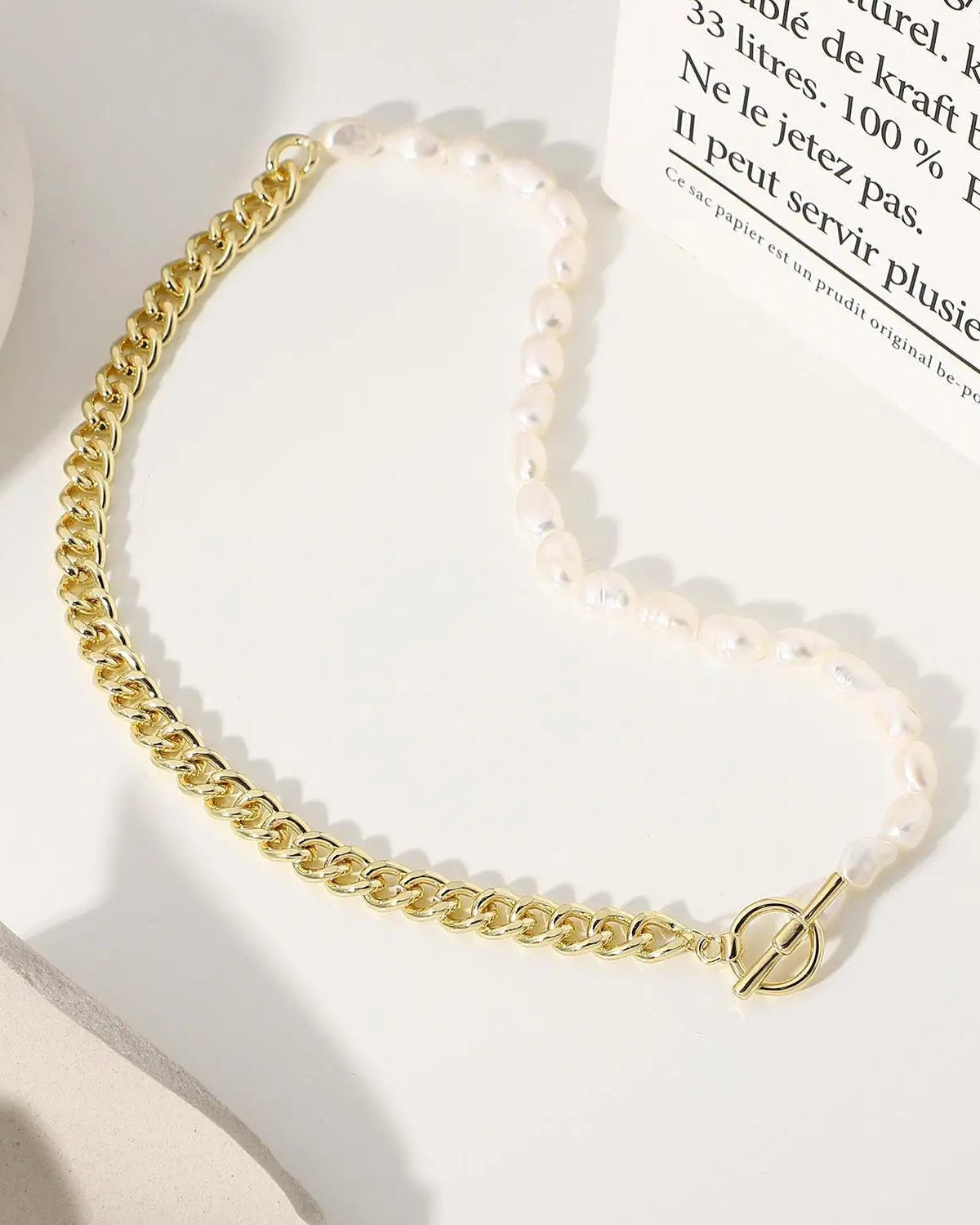 A necklace featuring natural baroque freshwater pearls on an asymmetric 14K gold-filled link chain with a cross motif, designed for a modern look.