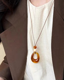 A vintage-inspired rope necklace featuring a lightweight hollow resin circle pendant, designed with a long chain for a relaxed, bohemian drape.