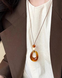 A vintage-inspired rope necklace featuring a lightweight hollow resin circle pendant, designed with a long chain for a relaxed, bohemian drape.