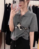 A cat-pattern collared wool knit top with turn-down collar, cat motif and half-length sleeves, designed for a cozy winter layering look that pairs from sneakers to boots.