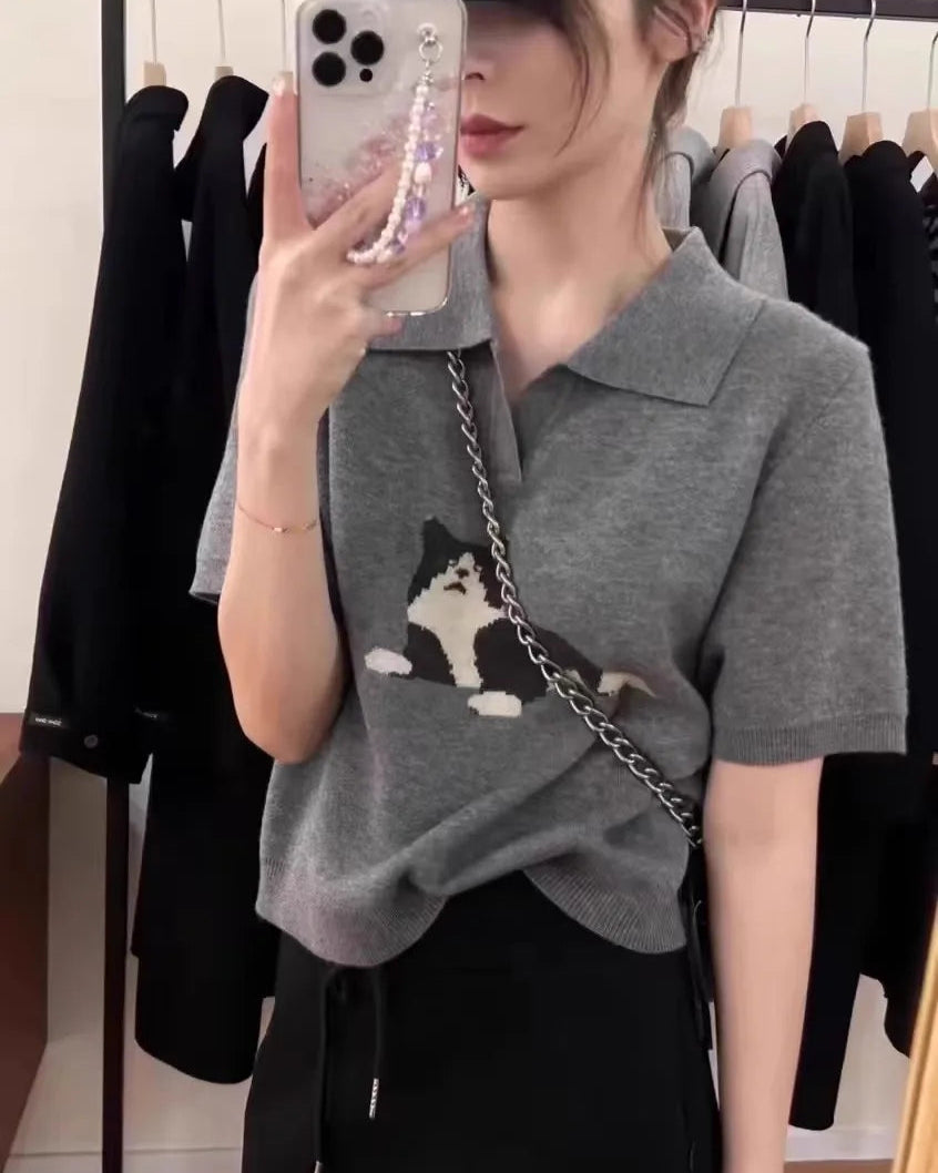 A cat-pattern collared wool knit top with turn-down collar, cat motif and half-length sleeves, designed for a cozy winter layering look that pairs from sneakers to boots.