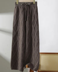 A pair of merino wool jacquard wide-leg trousers featuring a retro geometric pattern, a mid-rise waist, and a fluid, seamless knit silhouette.