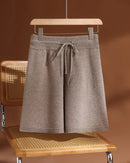 A pair of merino wool drawstring knit shorts featuring an elastic waist, a seamless construction, and an above-knee length for effortless comfort.