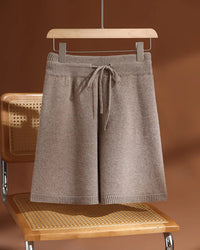 A pair of merino wool drawstring knit shorts featuring an elastic waist, a seamless construction, and an above-knee length for effortless comfort.